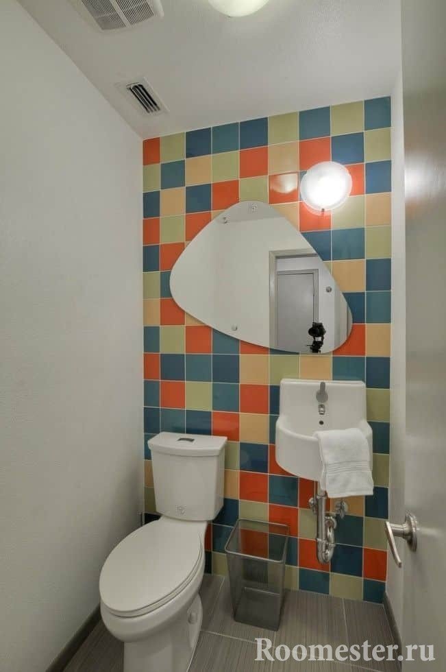 Pequeño inodoro con azulejos brillantes y paredes pintadas.