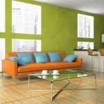 Sofá naranja con almohadas azules en el fondo de una pared de pistacho
