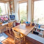 Una mesa con una computadora junto a la ventana