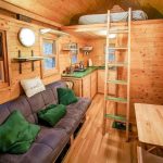Una habitación con cocina, sofás y una cama en el segundo piso.