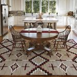 Cocina con muebles blancos y una mesa marrón.