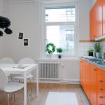 Cocina blanca con muebles de color naranja.