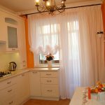 Paredes naranjas y muebles blancos en la cocina.