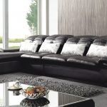 Sofá negro con almohadas brillantes en la habitación.