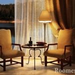 Mesa, lámpara y sillones junto a la ventana.