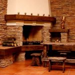 Mesa de madera y bancos junto a la chimenea.