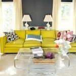 Mesa transparente y sofá amarillo en el interior.