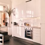 Piso negro y muebles blancos en la cocina.