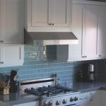Cocina con muebles blancos y un delantal azul claro.