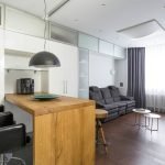 Muebles blancos y mesa de madera en un apartamento tipo estudio.