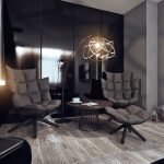 La sala es de color oscuro con una lámpara, una mesa y sillones.