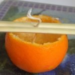 Pon la mecha en el centro de la mandarina.