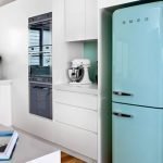 Muebles blancos y un refrigerador turquesa en la cocina.