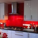 La combinación de muebles grises y un delantal rojo.