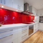 Muebles blancos y delantal rojo en el interior de la cocina.