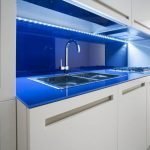Muebles de cocina blancos con delantal azul.