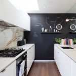 Muebles blancos y paredes negras en la cocina.