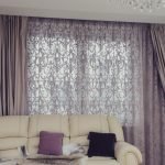Habitación con un sofá blanco y cortinas moradas.