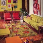 Habitación con sofá verde y sillones rojos.