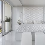 Cama blanca en el dormitorio con una gran ventana