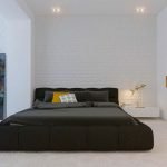 Cama oscura en un interior blanco.
