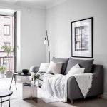 Sofá gris con almohadas blancas.