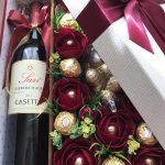 Botella de vino, flores y dulces.