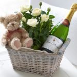 Champán, oso y flores en una canasta de regalo