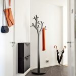 Percha negra con forma de árbol en un interior blanco