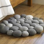 Alfombra hecha de piedras junto a la cama.