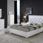 La combinación de paredes oscuras y muebles blancos en el dormitorio.