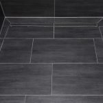Azulejo gris con costuras blancas en el piso.