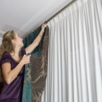 Niña cuelga cortinas
